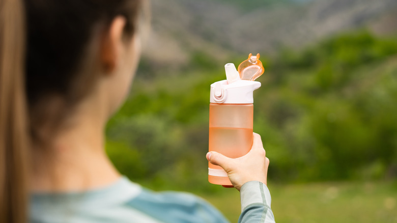 Woman holding an open, reusable water bottle