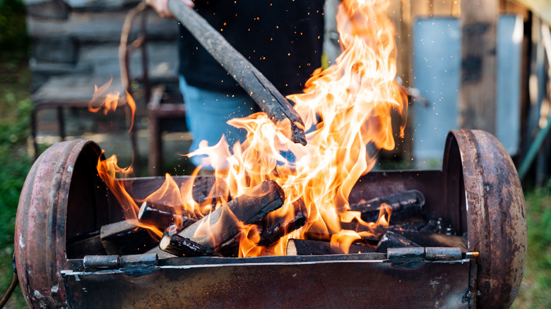 a wood fire being poked with a stick outdoors