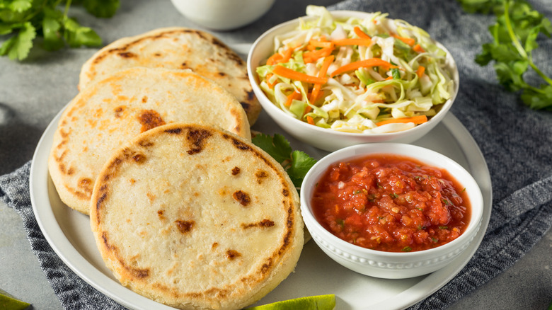 Pupusas on a plate with salsa and slaw