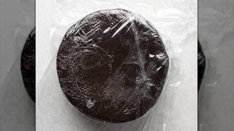 A cake layer wrapped in plastic wrap
