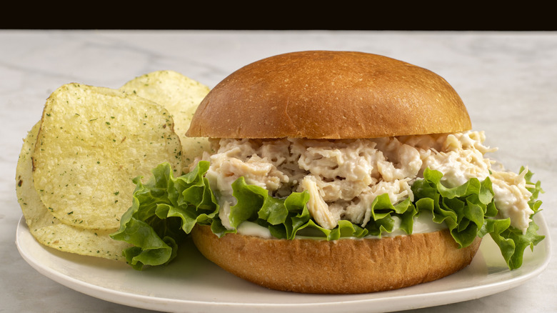 Chicken and lettuce sandwich on plate with potato chips