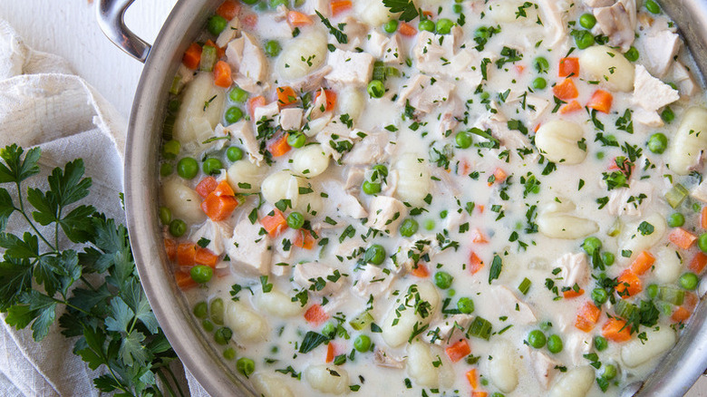 Chicken and dumplings in casserole pot, topped with chopped fresh parsley