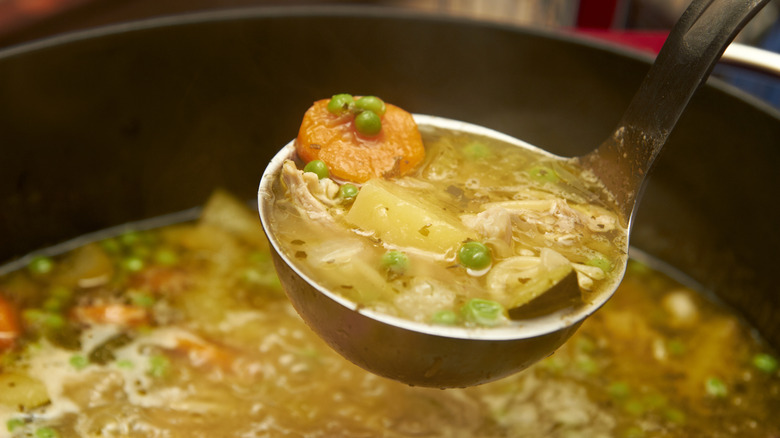 Ladleing chicken and vegetable soup from pot