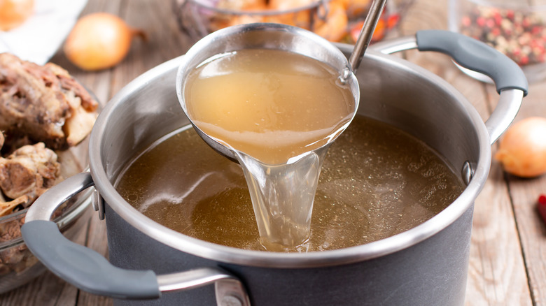 Ladle full of broth pours into pot