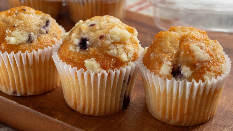 Row of three blueberry muffins still in paper wrappers