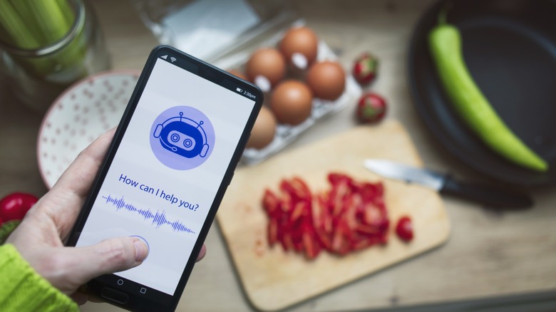 Someone accessing an AI chatbot on their phone with eggs and chopped peppers on a cutting board in the background