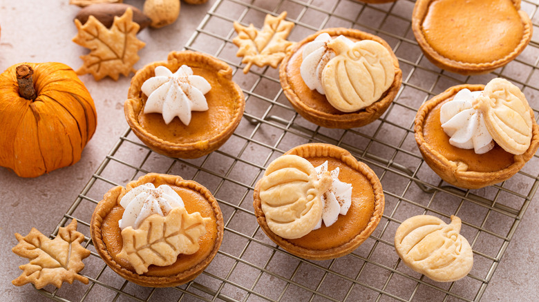 Mini pumpkin pies on rack topped with cookies and whipped cream