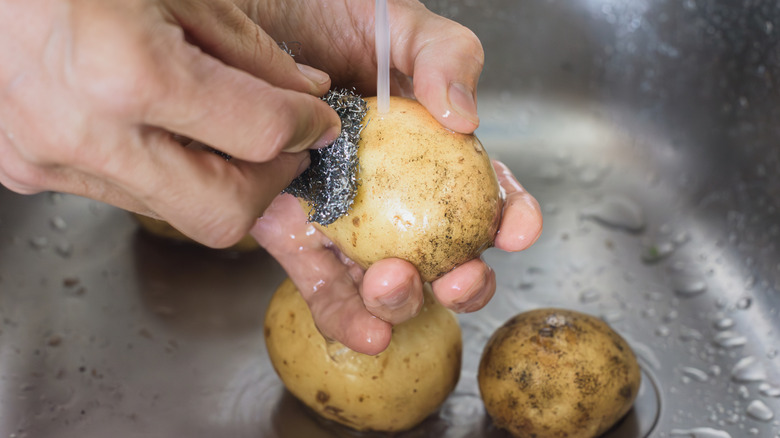 scrubbing potatoes in sink