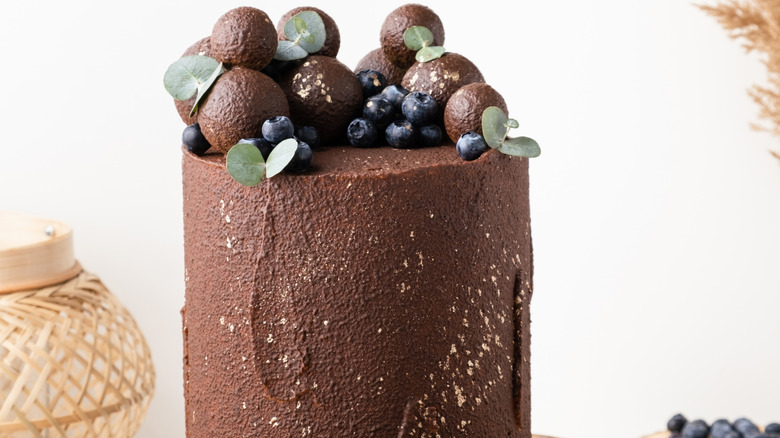 A black chocolate-wrapped cake on a white stand