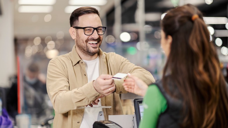 man handing cashier credit card