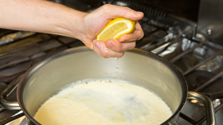 hand squeezing lemon in pot