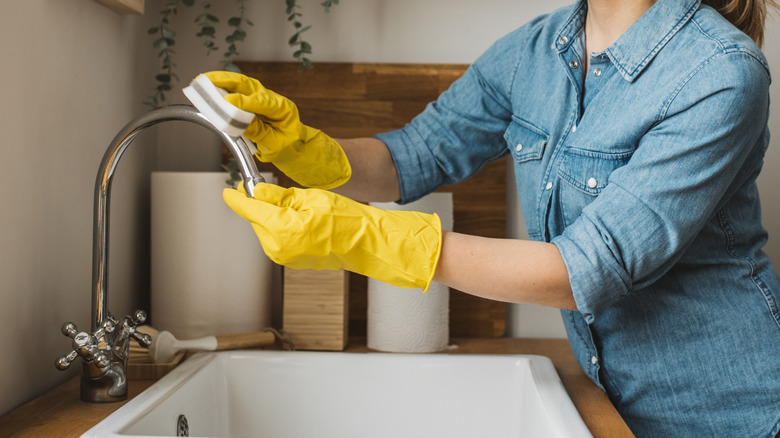 Woman cleaning kitchen sink faucet