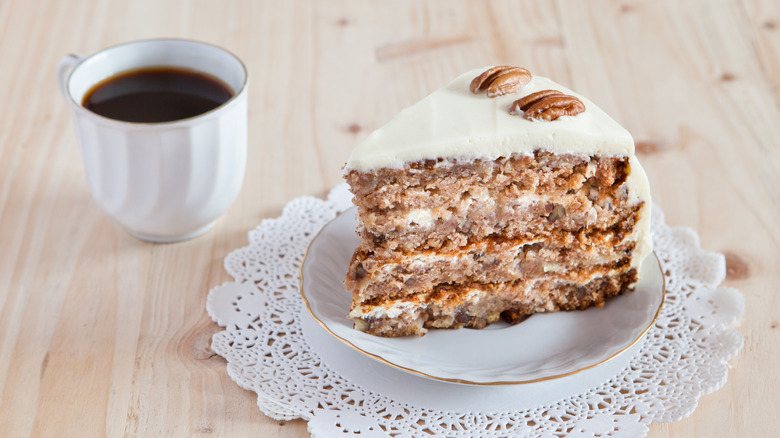 A slice of hummingbird cake on a plate next to a coffee