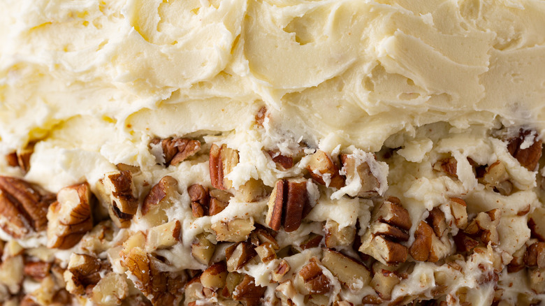 A close-up of the outside frosting and pecans on a hummingbird cake
