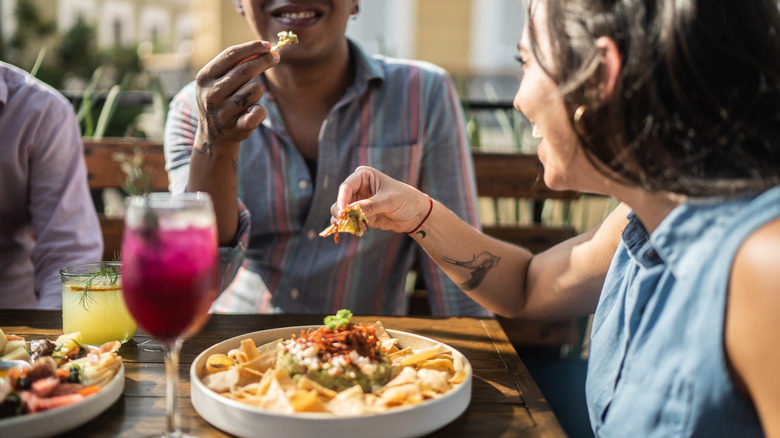 people sitting at table eating chips and dips