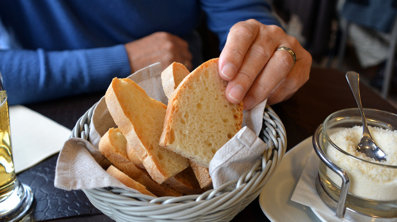 person grabbing bread form a bread basket