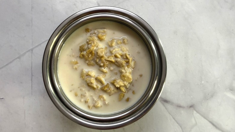 Steel bowl full of overnight oats with extra oat milk