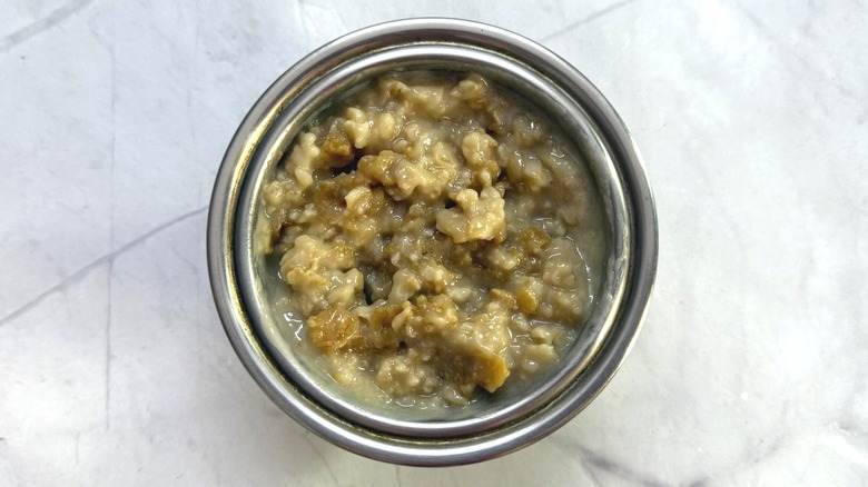 Steel bowl full of microwaved oatmeal with thick, slightly chewy texture
