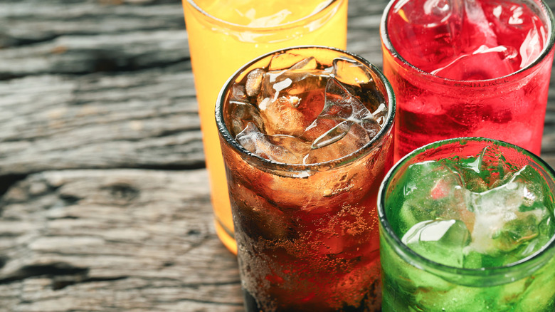 A close-up of colorful drinks with ice in glasses on a wood table