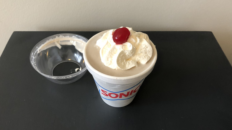 Sonic chocolate milkshake with whipped cream and cherry.