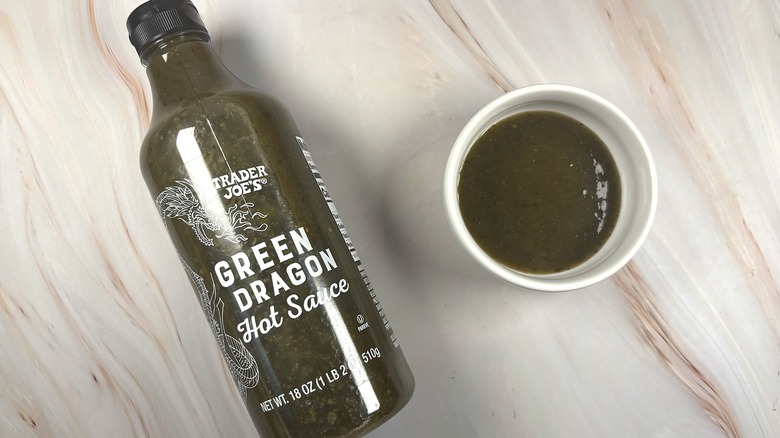 Overhead shot of Trader Joe's Green Dragon Hot Sauce in white dish next to bottle on table