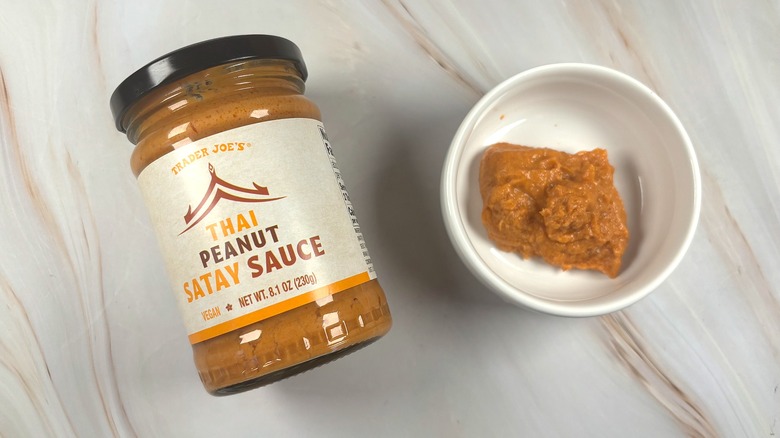 Overhead shot of Trader Joe's Thai Peanut Satay Sauce in white dish next to jar on table