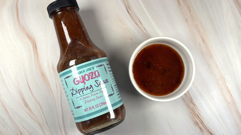 Overhead shot of Trader Joe's Gyoza Dipping Sauce in white dish next to bottle on table