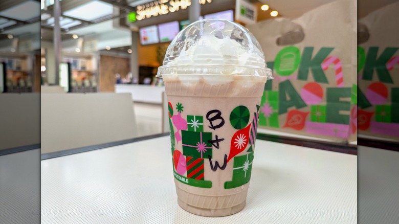 Vanilla custard is blended with a chocolate fudge sauce creating a light brown milkshake topped with whipped cream in a disposable cup