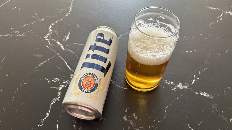 A can of Miller Lite with a glass of beer next to it on a black counter