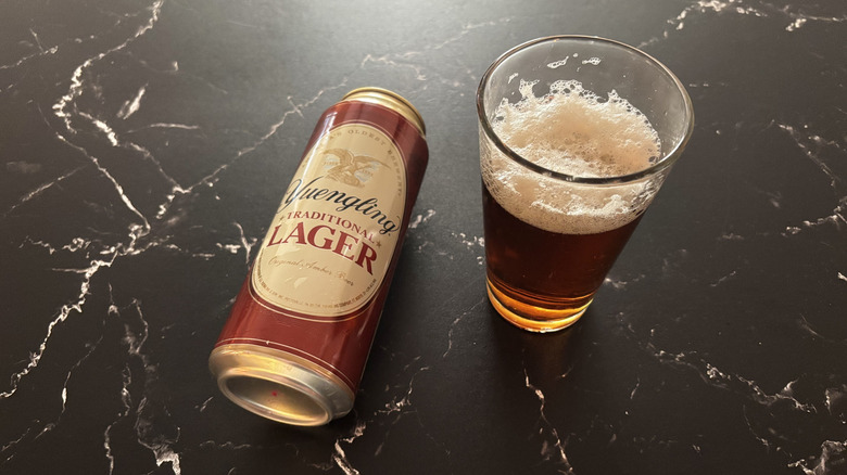 Yuengling beer can displayed next to glass of beer on black marble