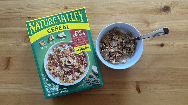 Nature Valley Apple Cinnamon cereal box with some cereal in a white bowl mixed with milk