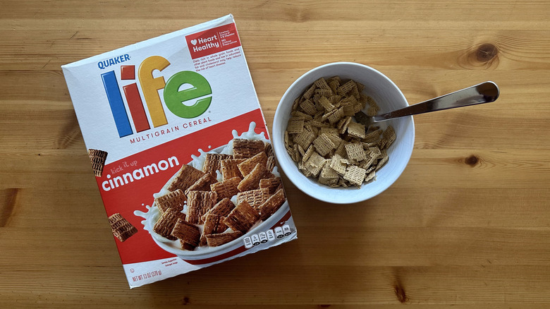 Life Cinnamon cereal in white bowl on table with a cereal box next to it