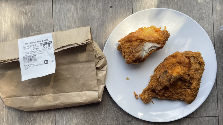 Fried chicken thigh and breast on a plate with brown paper bag container