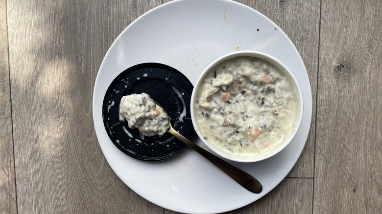 Chicken soup in an open container with a plate and spoon