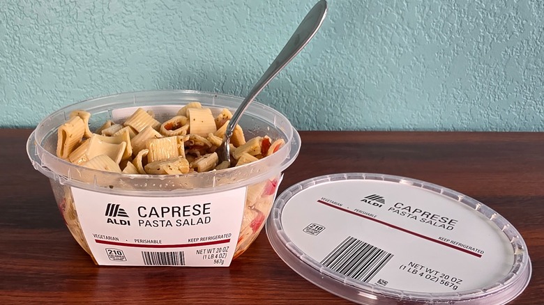 Container of Aldi Caprese pasta salad open on table with spoon
