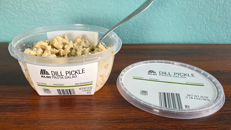 Container of Aldi dill pickle pasta salad open on table with spoon