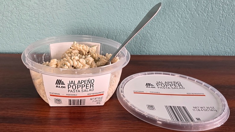Container of Aldi jalapeño popper pasta salad open on table with spoon