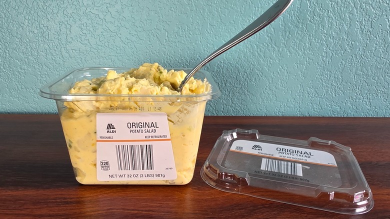 Container of Aldi original potato salad open on table with spoon