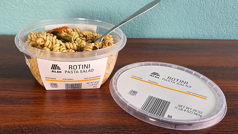 Container of Aldi rotini pasta salad open on table with spoon