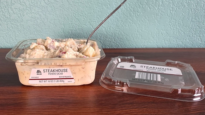 Container of Aldi steakhouse potato salad open on table with spoon