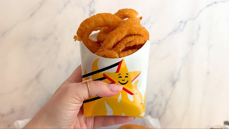 Hand holding Carl's Jr. Onion Rings against white background