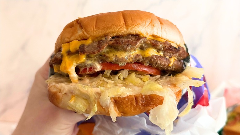 Hand holding Carl's Jr. Cali XL against white background