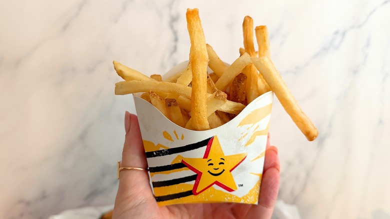 Hand holding Carl's Jr. french fries against white background