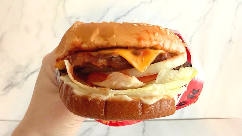Hand holding Carl's Jr. Single Famous Star against white background
