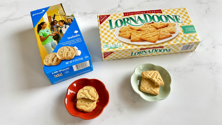 Girl Scout Trefoils cookie box next to Lorna Doone cookie box with cookies on plates in front