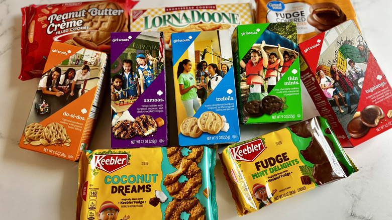 Various Girl Scout cookie boxes and store-bought cookie packages on countertop