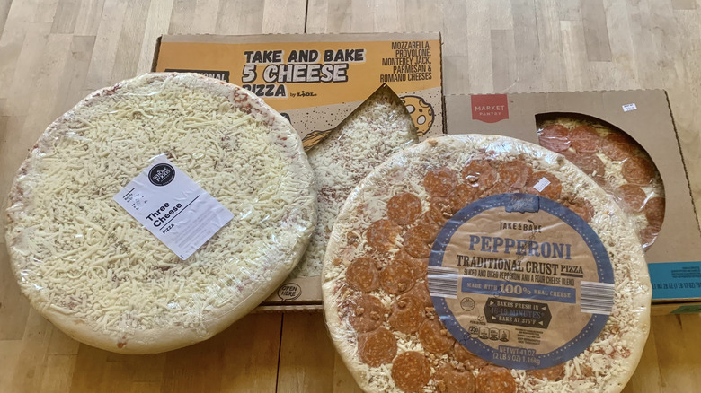 four packaged uncooked pizzas on wood background