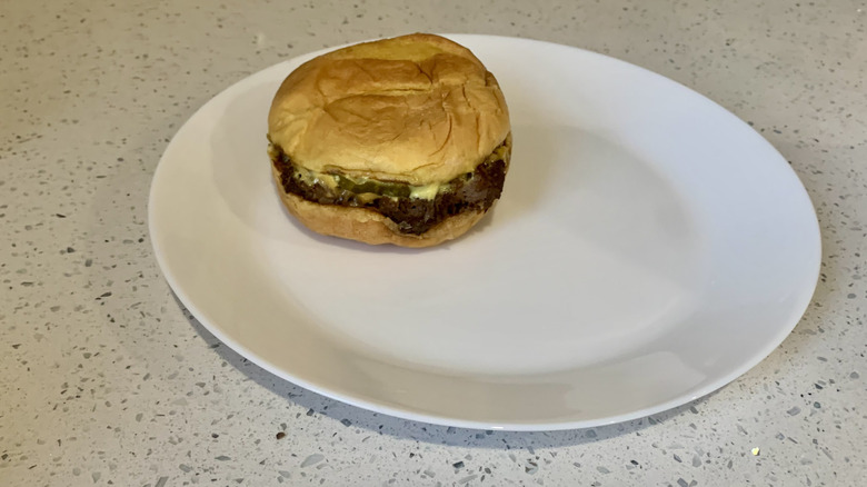 Smashburger burger on white plate on wood table
