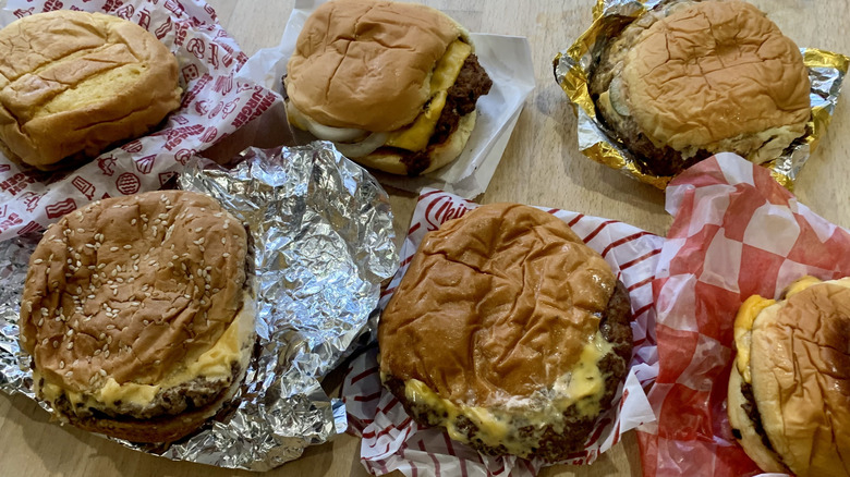 Six unwrapped smash burgers on wood table
