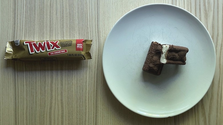 Twix Ice Cream Bar on white plate and a wrapper on a wooden counter